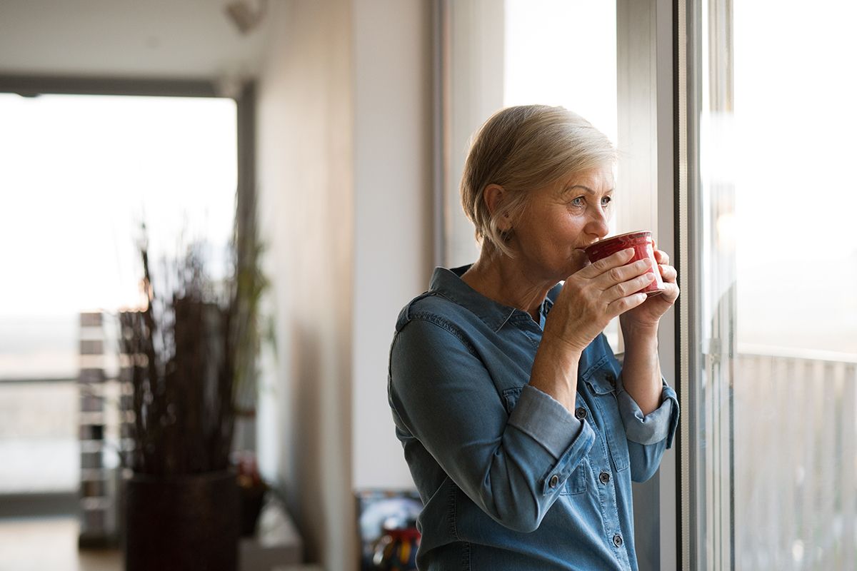 Senior tasse de caffé regarde fenêtre